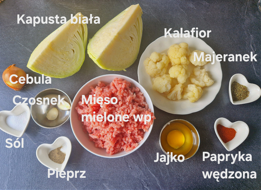 Ułożone na ciemnym blacie składniki na keto gołąbki bez zawijania. Mięso mielone, kapusta, czosnek, sól, pieprz, kalafior, majeranek, jajko, papryka wędzona