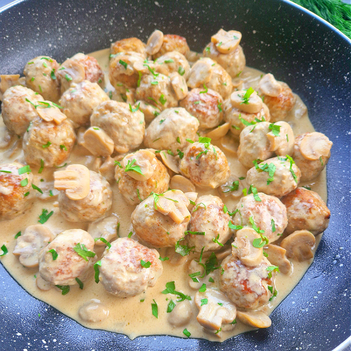 Keto pulpety w sosie pieczarkowo-śmietanowym na patelni posypane natką pietruszki