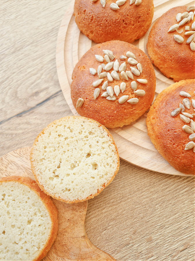 Przekrój keto bułeczki. Miękki i puszysty środek bez glutenu. Bułeczki ułożone na drewnianym blacie.