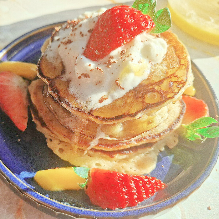 Zdjęcie główne placuszków pancakes z dojrzałych bananów z owocami na niebieskim talerzyku.