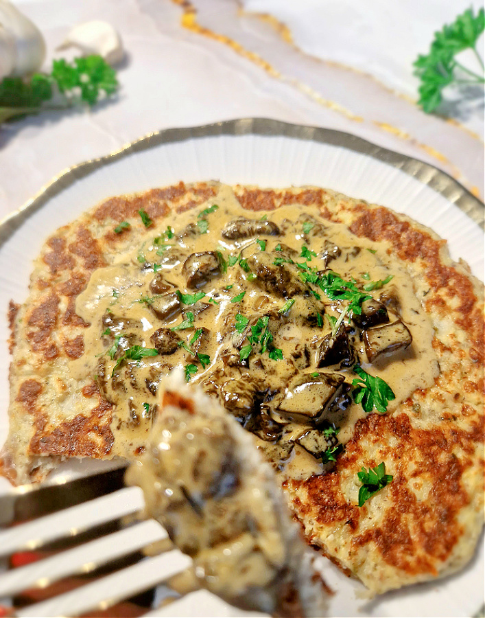 Porcja placków kalafiorowych podana z sosem grzybowym i natką pietruszki