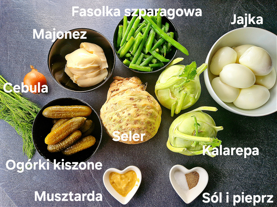 Składniki do przygotowania keto sałatki jarzynowej ułożone na ciemnym blacie w miseczkach. Seler, kalarepa, jajka, ogórki kiszone, fasolka zielona, majonez, cebul, musztarda i przyprawy