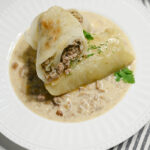 Gołąbki low carb z mięsem i kalafiorem w sosie grzybowym na białym talerzu ujęcie z góry