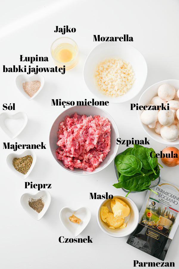 Składniki potrzebne do przygotowania kieszonek z mięsa mielonego ułożone na blacie: mięso mielone, jajko, przyprawy, warzywa i dodatki.