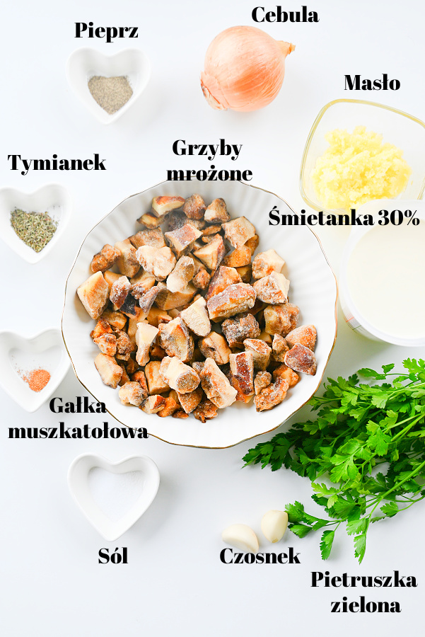 Składniki na sos: mrożone, podgrzybki w misce, pojemnik śmietanki, ząbki czosnku, cebula i tymianek na jasnym tle.