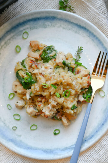 Porcja kurczaka po toskańsku z makaronem orzo, szpinakiem i suszonymi pomidorami na talerzu.