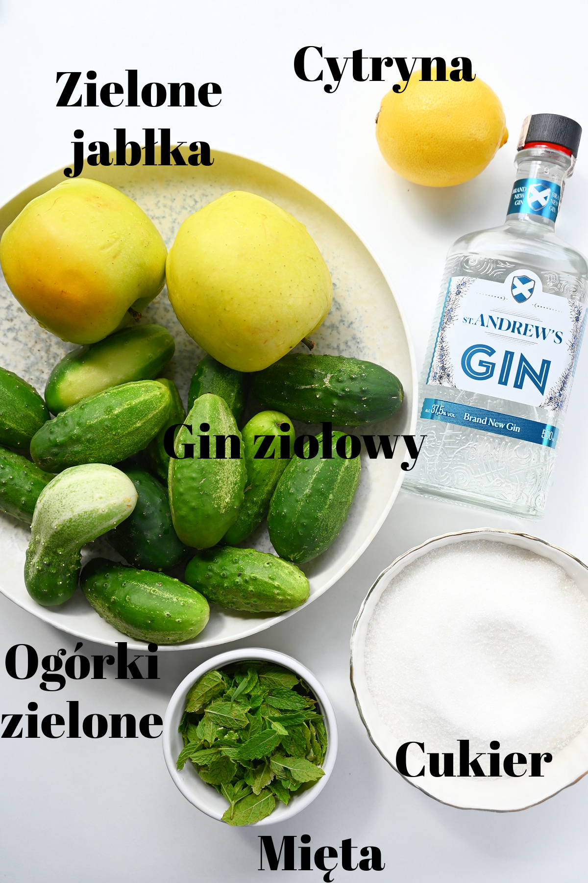 Składniki na dżem z ogórka: jabłka, ogórki, cytryna, mięta, cukier i dżin z czarnymi podpisami.